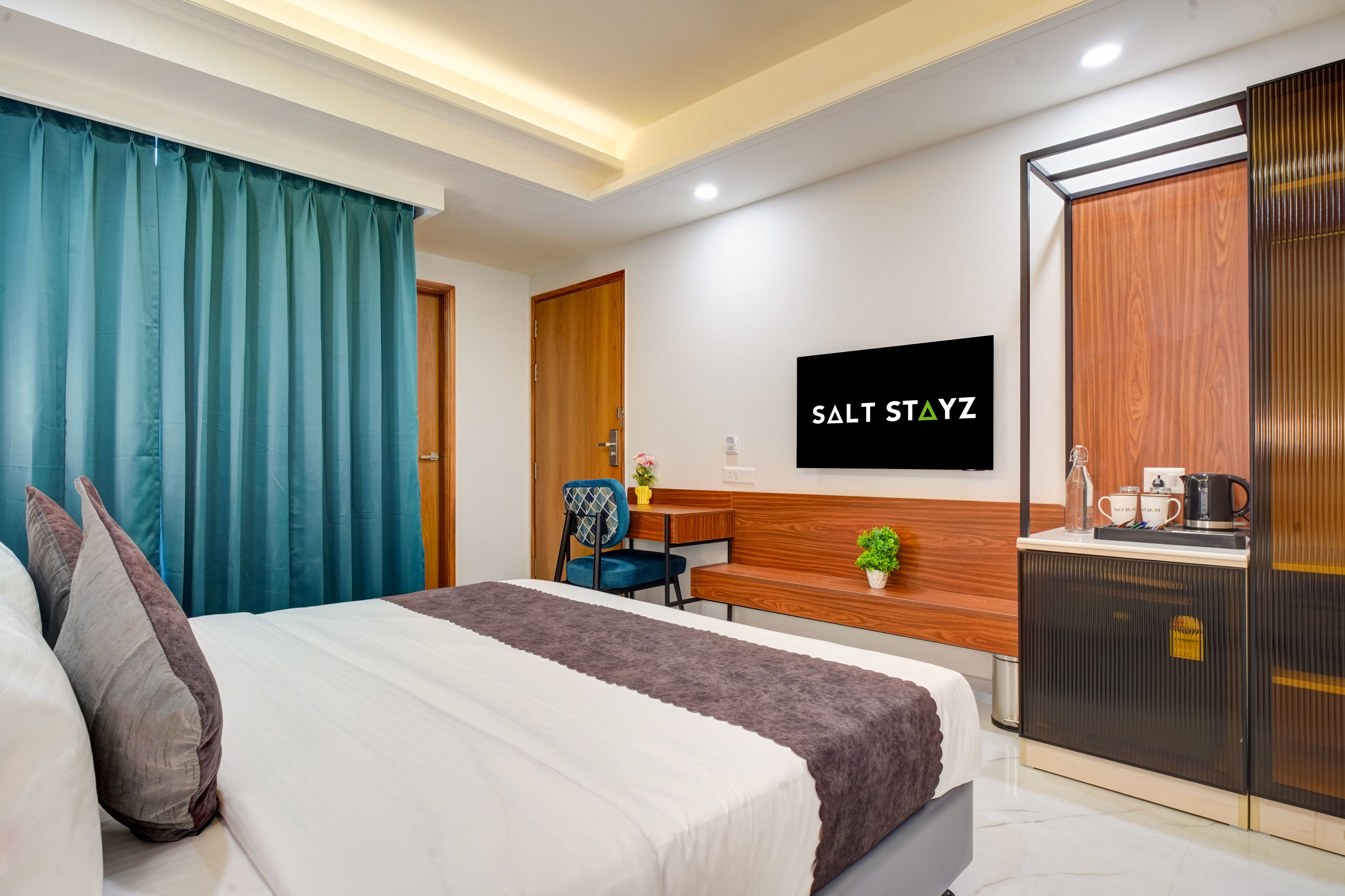 A hotel room with a bed, a desk, a chair, a TV, and a wardrobe.