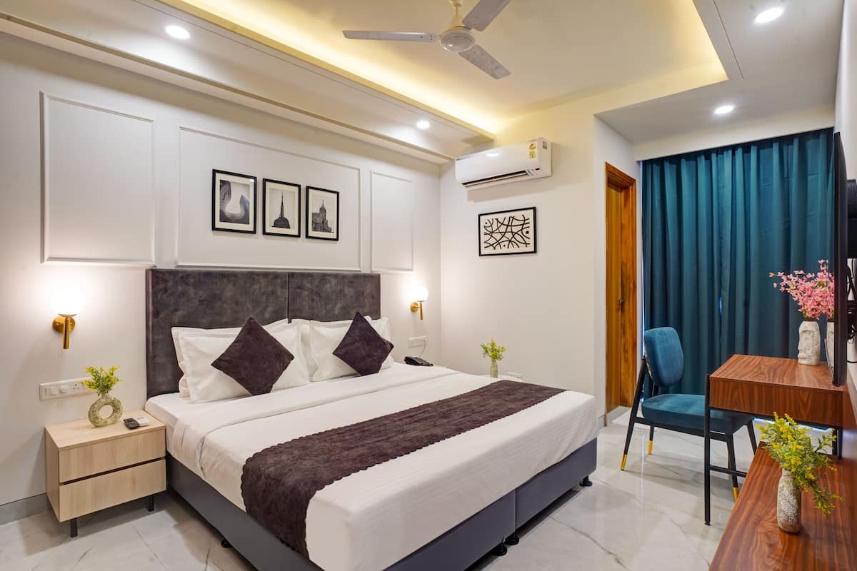 A modern hotel room with a large bed, bedside tables, a desk, and a chair.