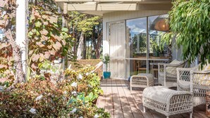 A covered outdoor area with wicker furniture, a glass door leading inside, and a pergola with vines. - Sky Views by Property Mums (Somers)