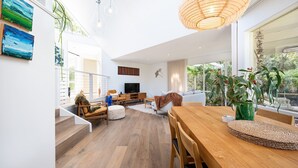 A spacious living area with a wooden dining table, comfortable seating, and a television. - Sky Views by Property Mums (Somers)