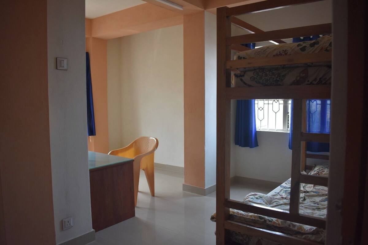 A room with bunk beds, a desk, and a chair.