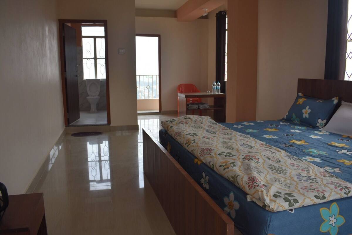 A bedroom with a bed, a desk, and a bathroom with a toilet and sink.