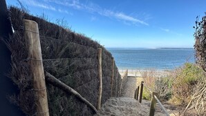 En sandstig som leder längs stranden, med trästolpar och ett trästaket.