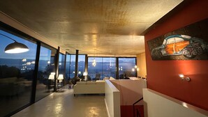 En modern inredning med stora fönster, en soffa, en matplats och en trappa.