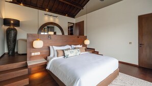 Ein modernes Schlafzimmer mit einem Holzkopfteil, einem großen Spiegel und einer eingebauten Sitzbank am Fußende des Bettes.