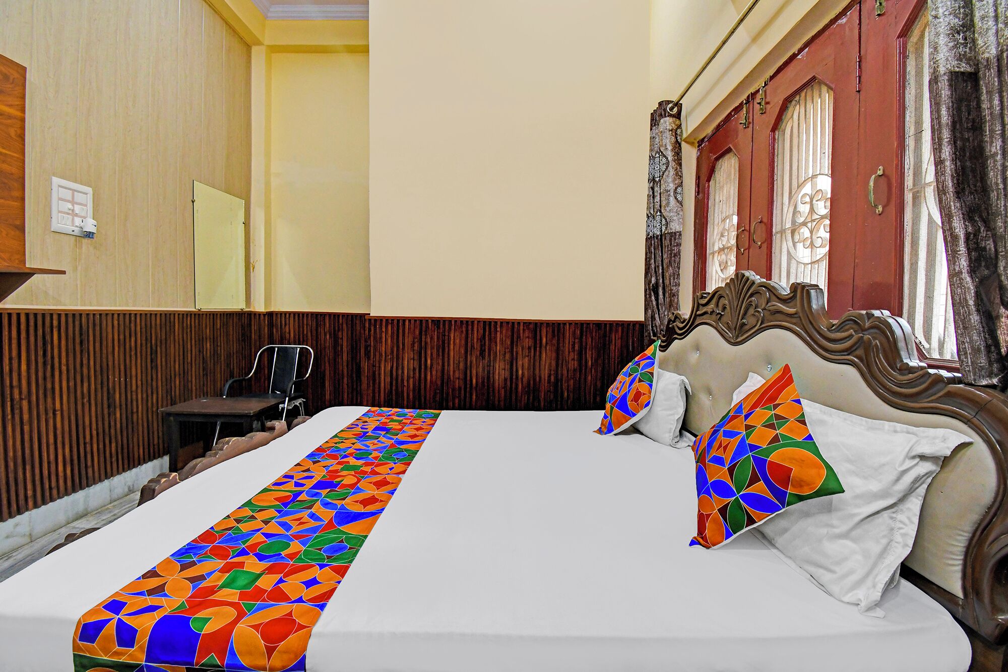 A hotel room with a large bed, a wooden desk, and a chair.