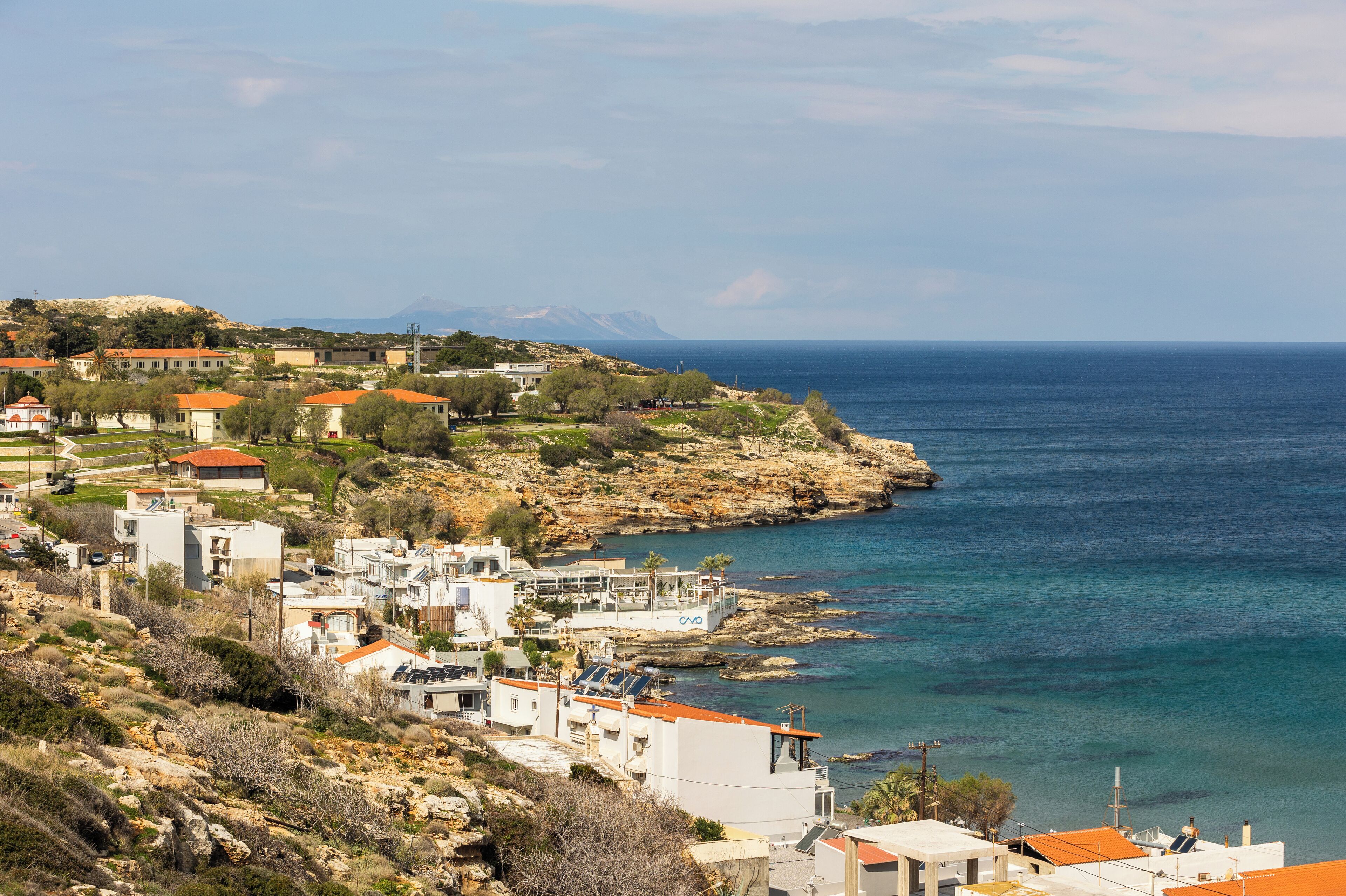 Une ville côtière avec des bâtiments le long du littoral, un terrain rocheux et une vue sur la mer.