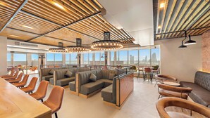 Un intérieur moderne avec des plafonds à lattes de bois, des coins salon et de grandes fenêtres offrant une vue sur la ville.