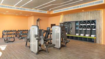 Un gimnasio con equipo de ejercicio, mancuernas y un perchero para toallas.