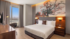 Une chambre d’hôtel moderne dotée d’un grand lit, d’un bureau et offrant une vue sur la ville.