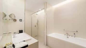 Un baño moderno con ducha envuelta en vidrio, una bañera blanca grande y un lavabo con espejo sobre encimera.