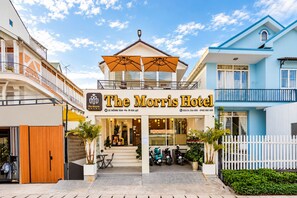The Morris Hotel with a prominent entrance, a covered outdoor seating area, and a white picket fence. - The Morris Hotel - Central Dalat (Xuan Huong - Da Lat)