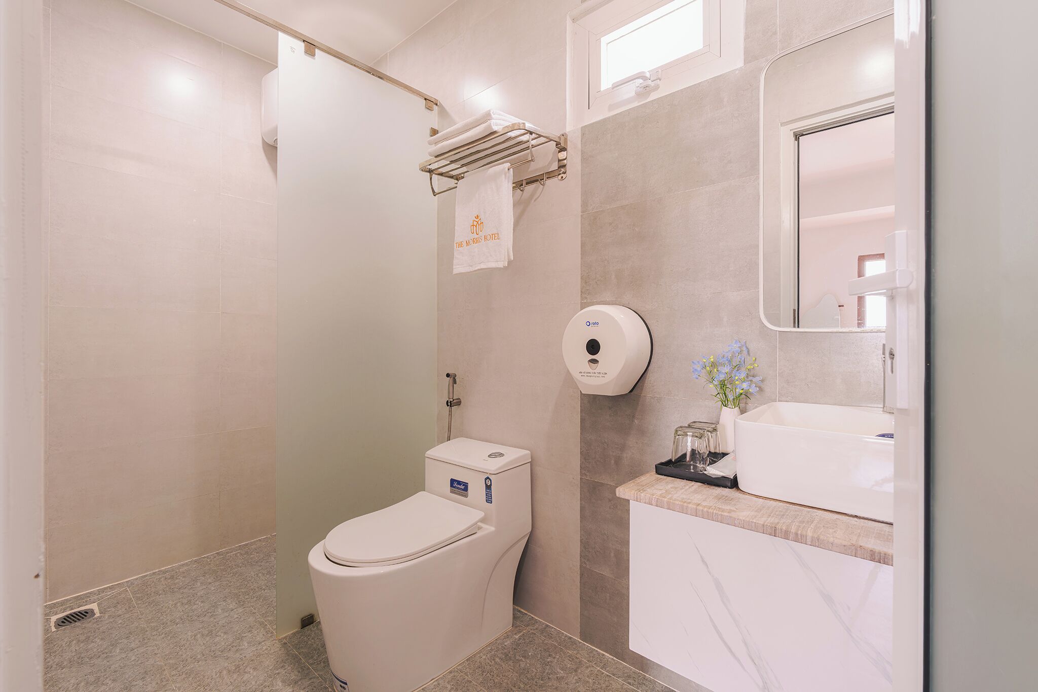 Un baño moderno con inodoro, secador de manos, lavamanos y espejo.