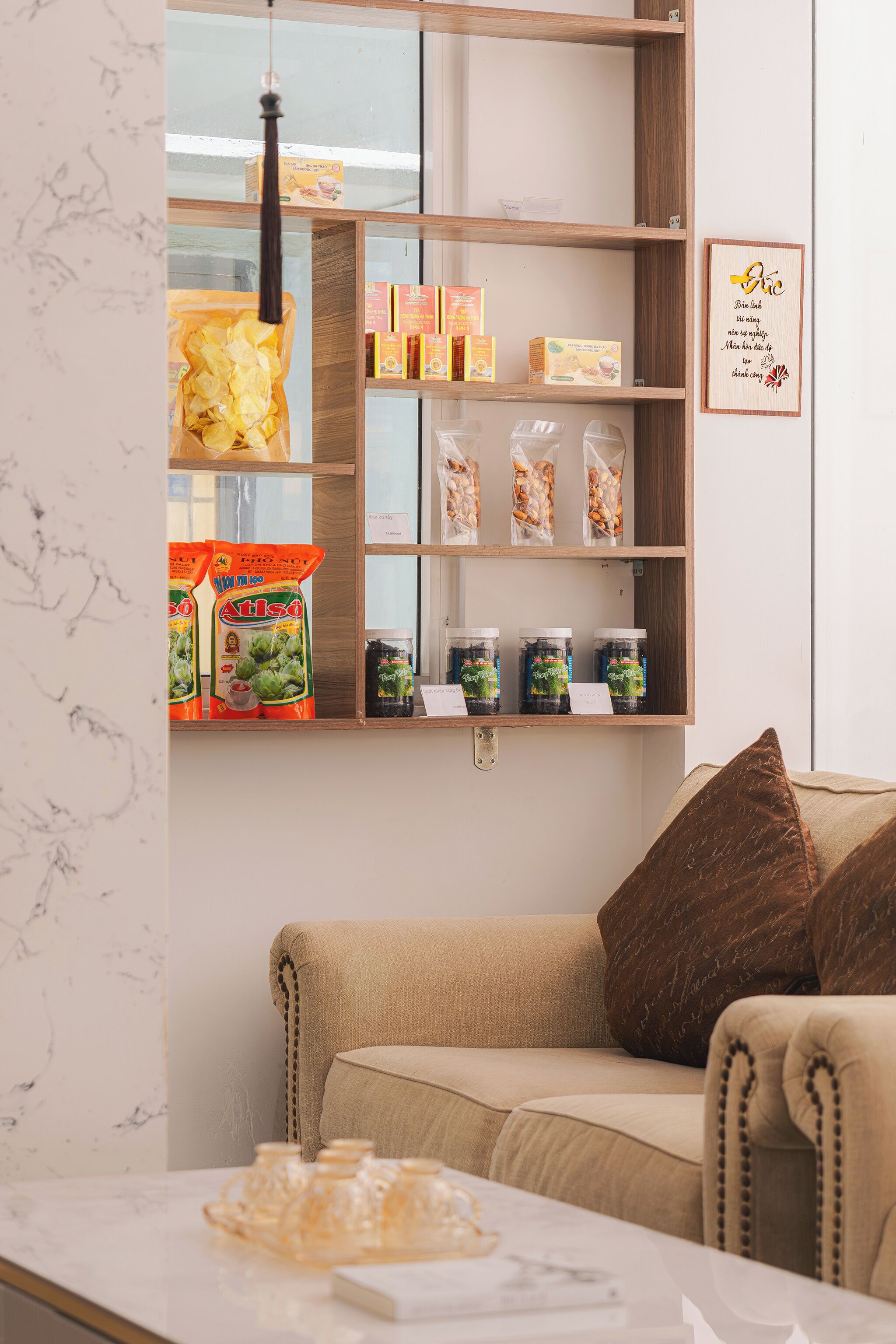 A cozy living area with a sofa, a marble table, and shelves stocked with snacks and condiments.