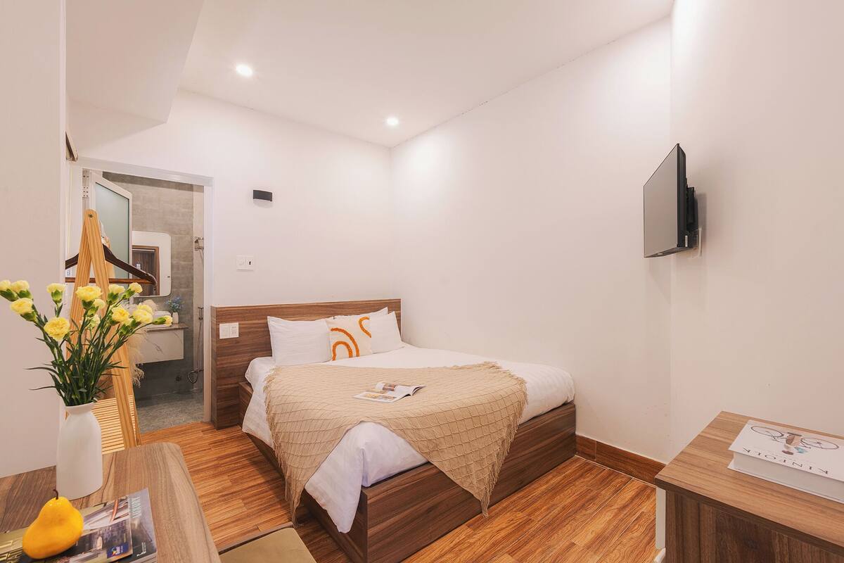 Une chambre d’hôtel moderne avec un lit en bois, un téléviseur à écran plat et un plancher en bois.