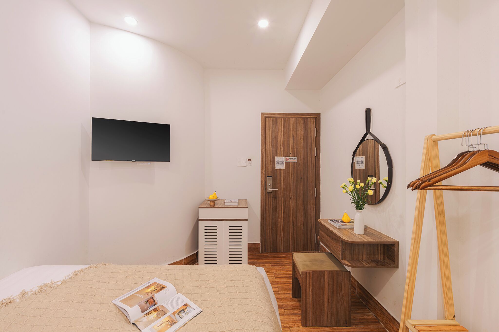 A modern bedroom with a bed, bedside table, TV, wardrobe, and a mirror.