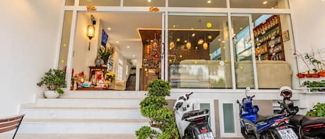 A storefront with a staircase leading up to the entrance, potted plants, and two motorcycles parked in front.