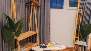 A room with a wooden chair, a small table, a mirror, and a potted plant. - The Morris Central Hotel - O'TEL (Xuan Huong - Da Lat)
