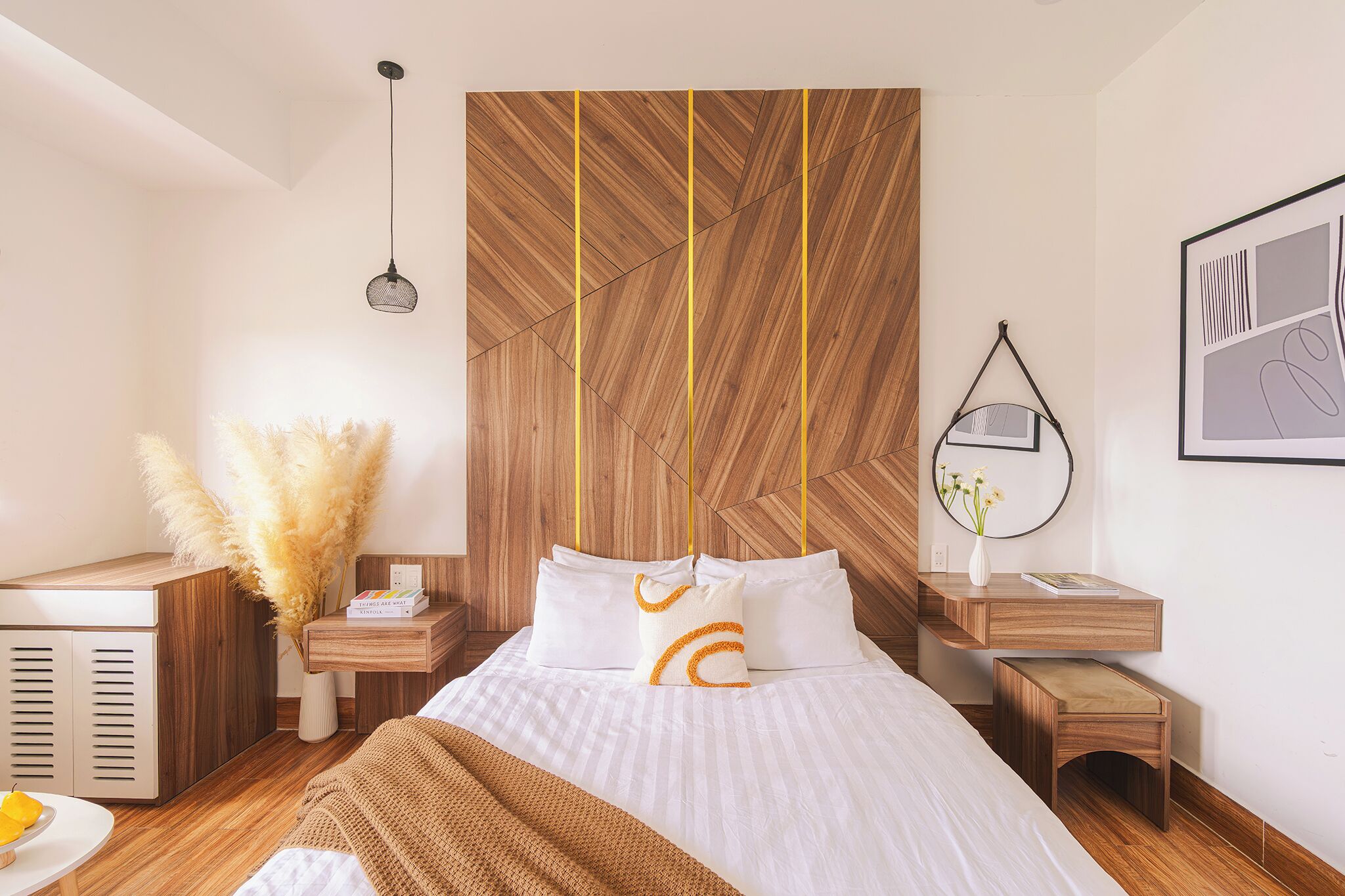 A modern bedroom with a wooden headboard, a bedside table with a lamp, a nightstand, and a small wooden stool.