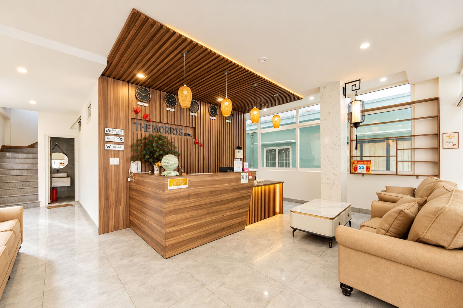A hotel reception area with a wooden reception desk, multiple clocks, and a seating area with sofas.