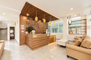 A hotel reception area with a wooden reception desk, multiple clocks, and a seating area with sofas. - The Morris Hotel - Central Dalat (Xuan Huong - Da Lat)
