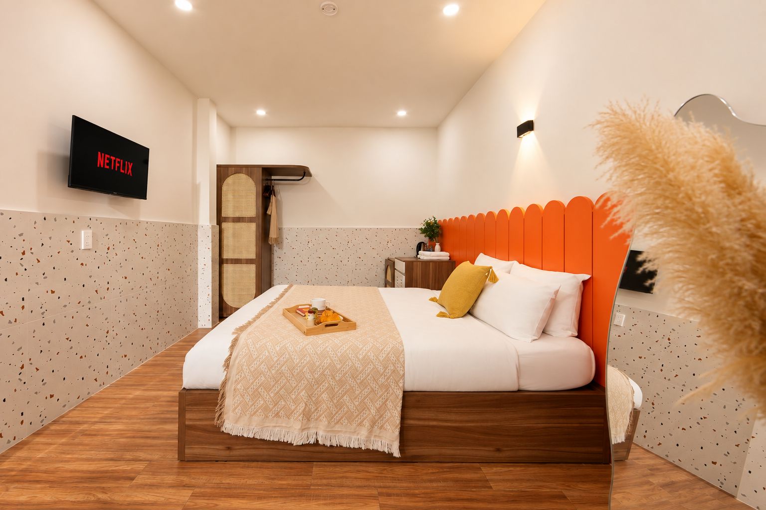 A modern bedroom with a bed, a bedside table, a wall-mounted TV, and a decorative wall panel.