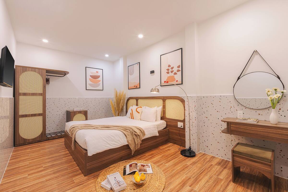 Une chambre à coucher moderne avec un lit en bois, des tables de chevet, un miroir rond et des œuvres d’art accrochées aux murs.