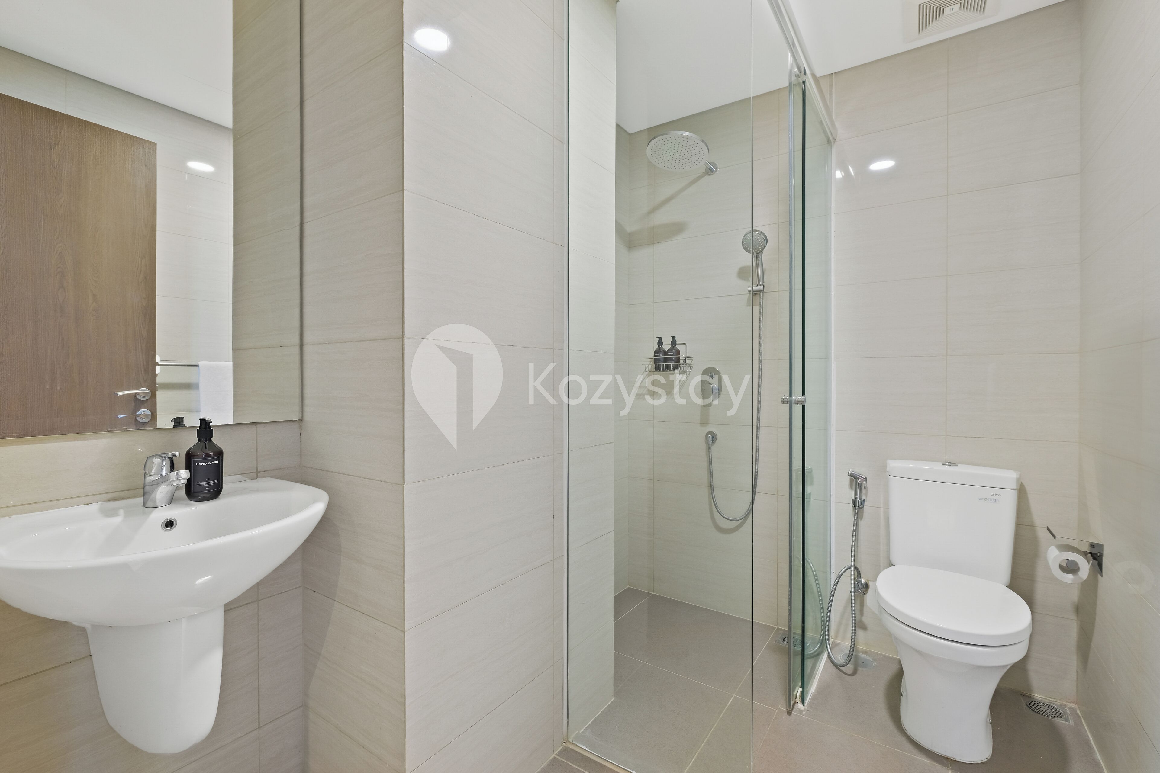 A modern bathroom with a white sink, a toilet, and a glass-enclosed shower area.