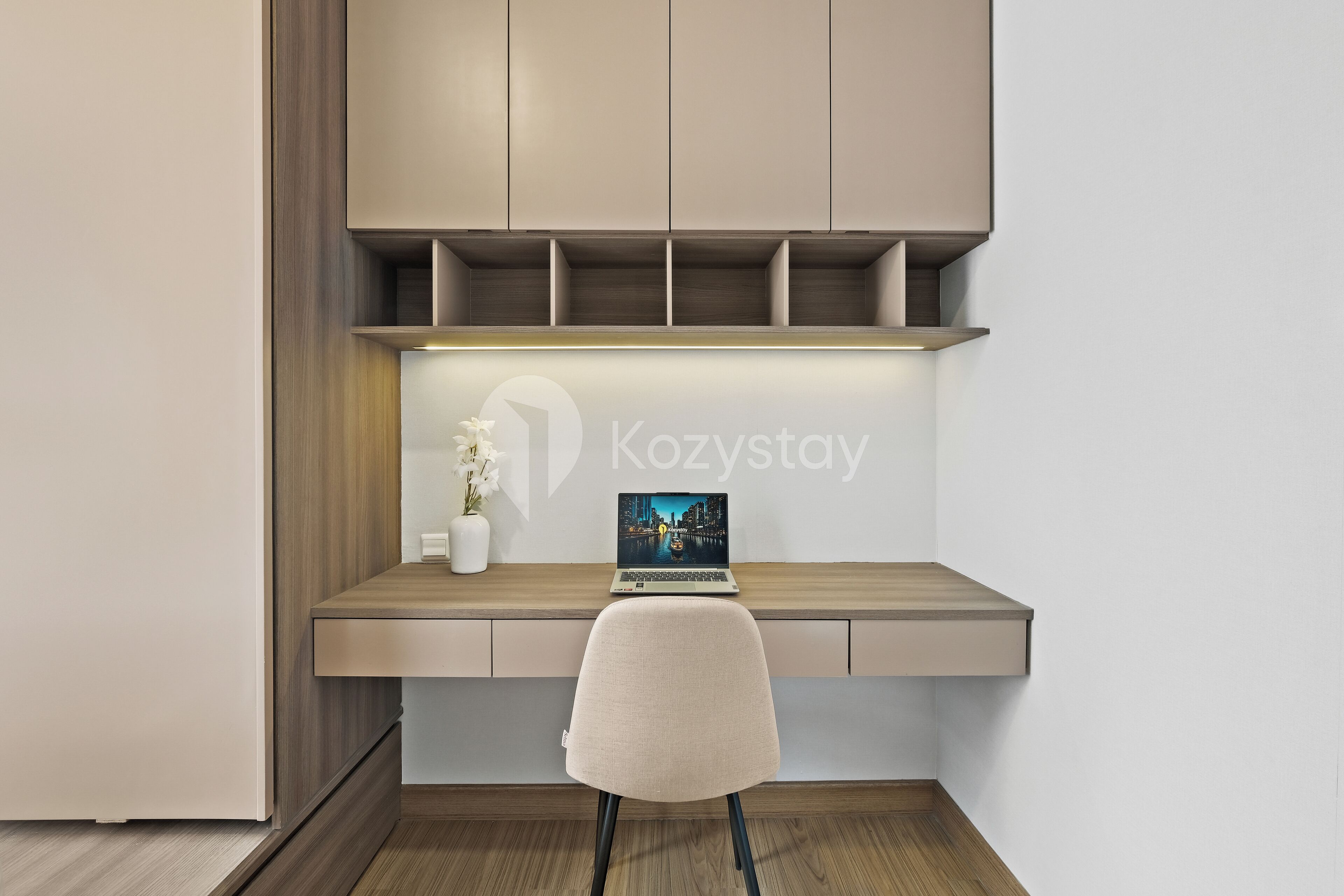 A modern workspace with a laptop on a wooden desk, a chair, and a shelf above.