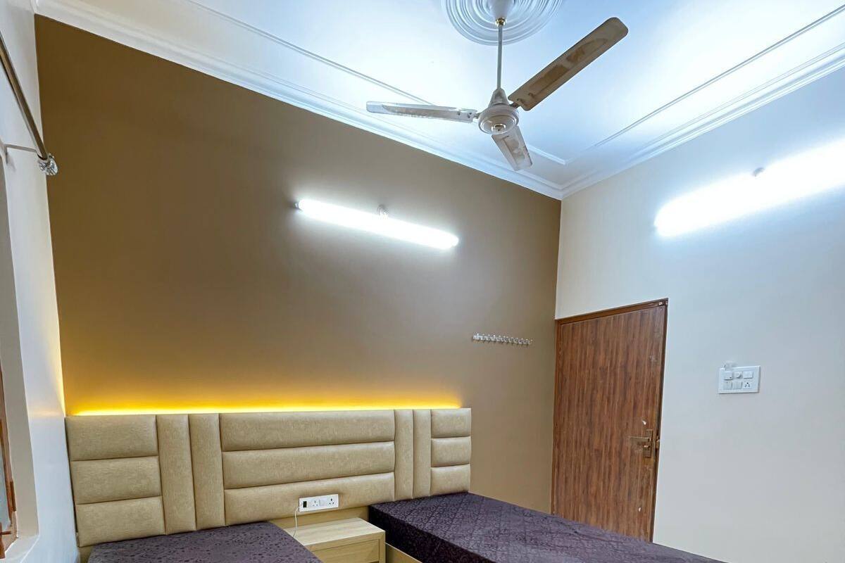 Un dormitorio con dos camas, un ventilador de techo, iluminación empotrada y una puerta de madera.