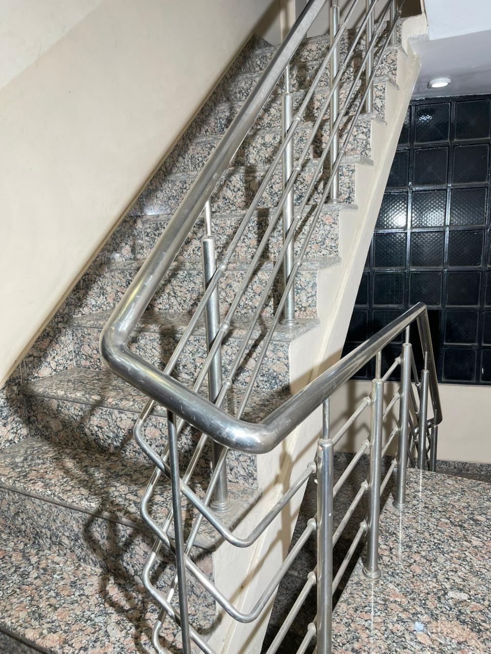 Una escalera con barandillas de metal y escalones de granito.