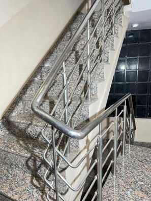 Una escalera con barandillas de metal y escalones de granito.