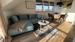 A modern living room with a sectional sofa, a round coffee table, and a dining area with chairs.