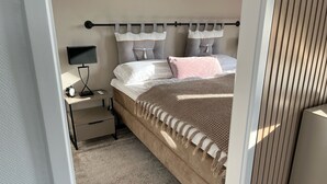 A bedroom with a bed, bedside table, lamp, and a window with blinds.