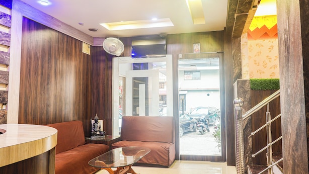 A reception area with a sofa, a glass table, a fan, and a staircase. - Hotel Kasturi Continental (Bhopal)
