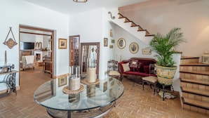 A spacious living area with a glass table, a red sofa, a staircase, and a potted plant. - Holiday Home Pozo Viejo (Marchena)