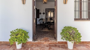 A doorway leading to a dining area with a table and chairs, flanked by two potted plants. - Holiday Home Pozo Viejo (Marchena)