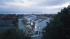 A modern residential building with multiple balconies, a courtyard, and a view of the surrounding neighborhood and mountains. - Erato Residential Complex-Two Bedroom Loft No Pool Access (Kavala)