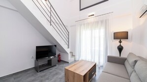 A modern living room with a staircase, a flat-screen TV, a wooden coffee table, a sofa, and a lamp. - Olympiada-Two Bedroom Loft No Pool Access (Kavala)