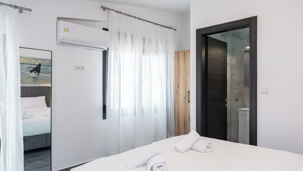 A modern hotel room with a large bed, a shower area, and a painting of a horse on the wall. - Olympiada-Two Bedroom Loft No Pool Access (Kavala)