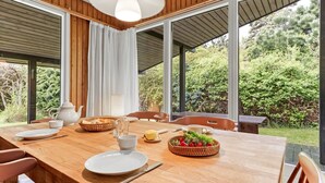 A dining area with a wooden table, chairs, and a view of greenery outside. - "Rikkart" - 400m from the sea by Interhome (Dannemare)