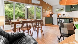 A cozy cabin interior with a dining area, kitchen, and a leather couch. - "Rikkart" - 400m from the sea by Interhome (Dannemare)