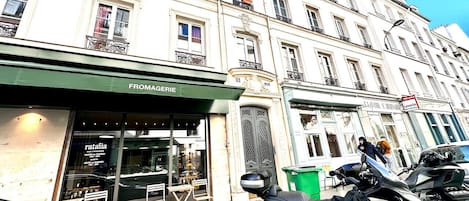 En byggnad med en butiksfasad där det står ”FROMAGERIE” och en parkerad motorcykel.