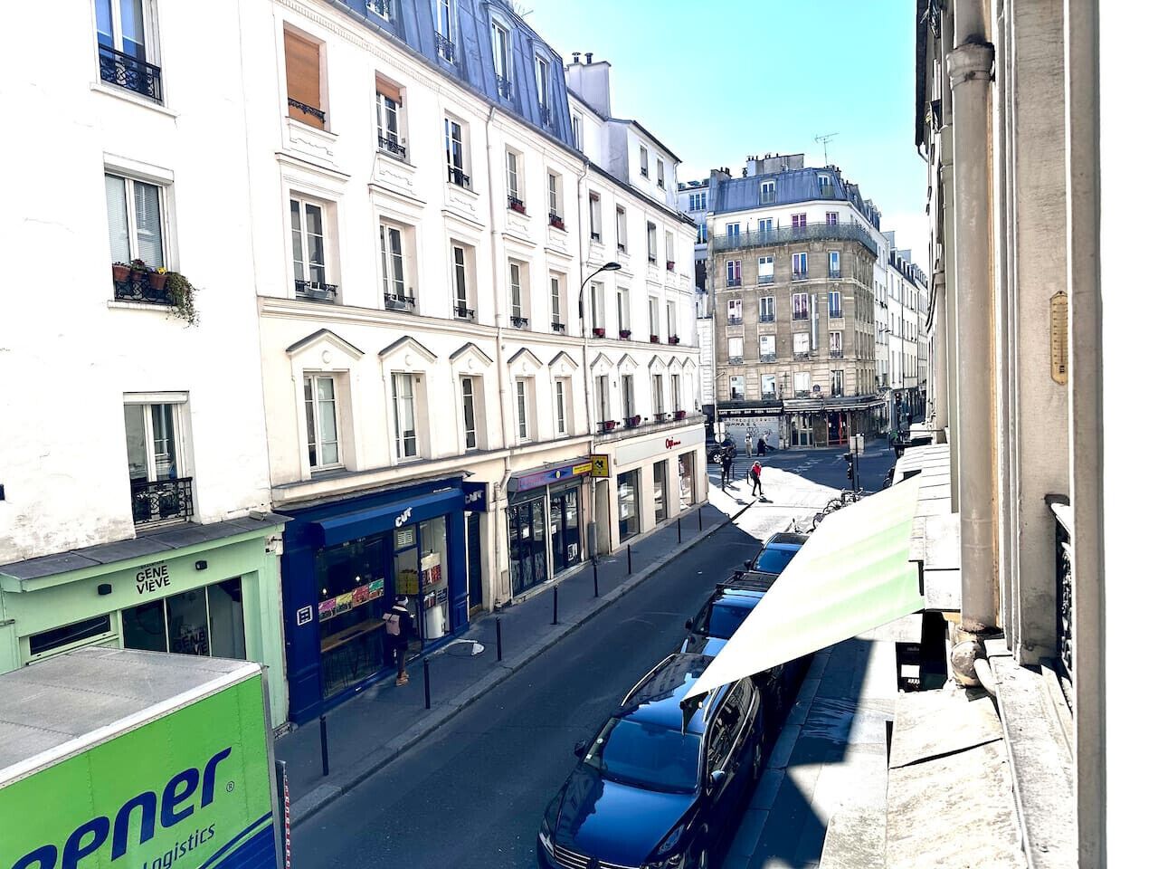 A street view with buildings, a parked truck, and a blue car.