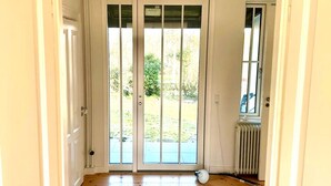 Een deur met uitzicht op een tuin, een radiator en een witte muur.