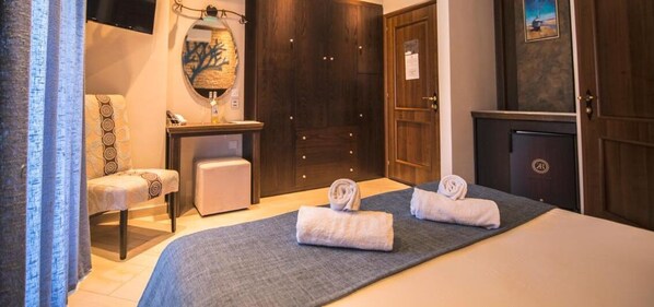 Une chambre d’hôtel comprenant un lit, deux serviettes, une chaise, un bureau, un miroir et une armoire.
