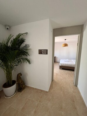 Un pasillo con una planta en maceta, una pequeña escultura y un cartel en la pared.