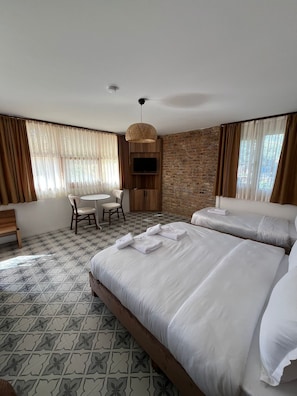 Habitación de hotel con dos camas, un escritorio, una silla, un televisor y piso con diseño.