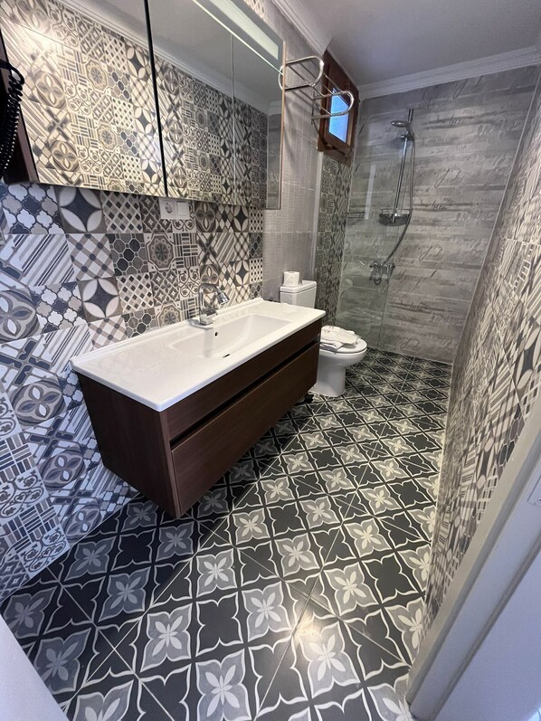 A bathroom with a large sink, a toilet, and a shower area. - kai urla (Urla)