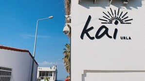 A building with a white facade, two air conditioning units on the roof, and a sign with the word "kai" and "URLA" on it. - kai urla (Urla)